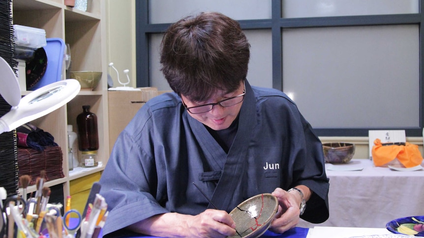 Jun using a thin brush to carefully apply red paint on top of the dried lacquer.