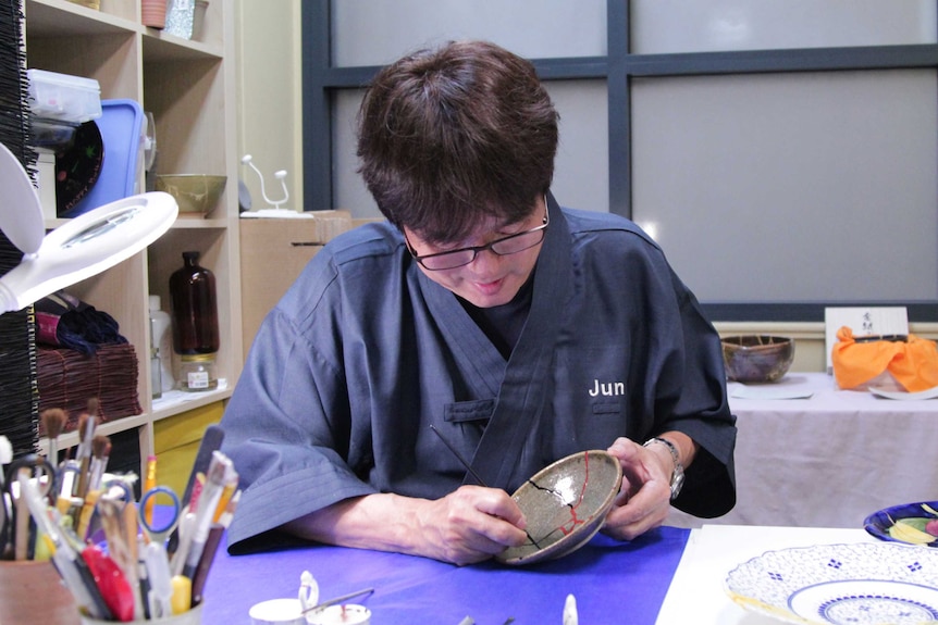 Jun uses a thin brush to carefully apply red paint on top of the dried lacquer.