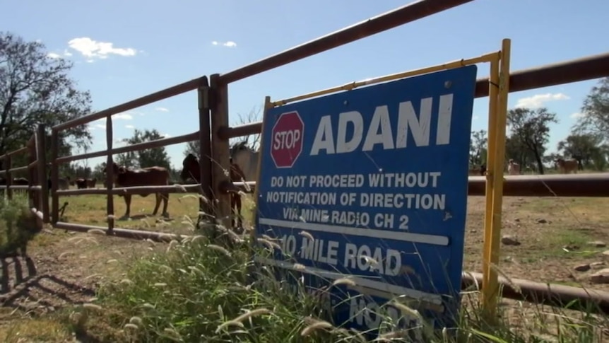 A stop sign bearing Adani's name leaning against a fence in central Queensland