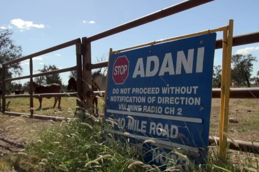 A stop sign bearing Adani's name leaning against a fence in central Queensland