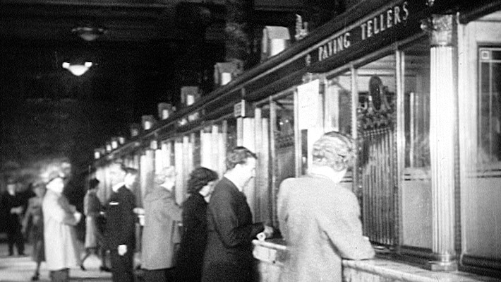 Customers being served by bank tellers in the 1950s.