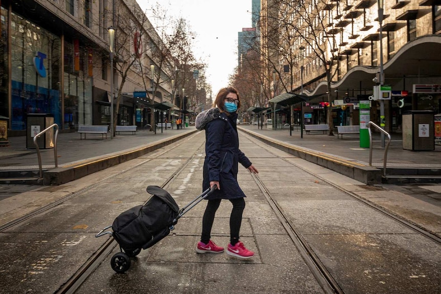 A woman with a bag crosses an empty Melbourne CBD street.