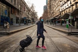 A woman with a bag crosses an empty Melbourne CBD street.