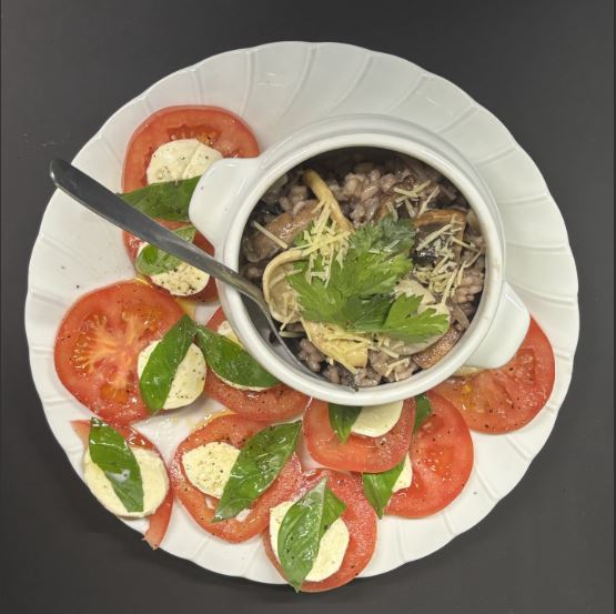 Mushroom risotto garnished with parmesan cheese and parsley, served with a caprese salad on the side. 
