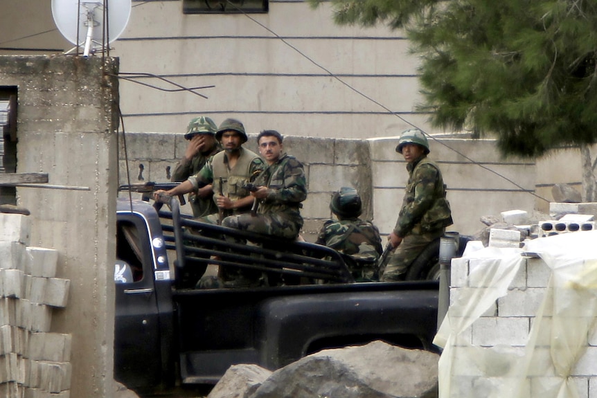 Syrian soldiers patrol the Syrian side of the border village of Arida.