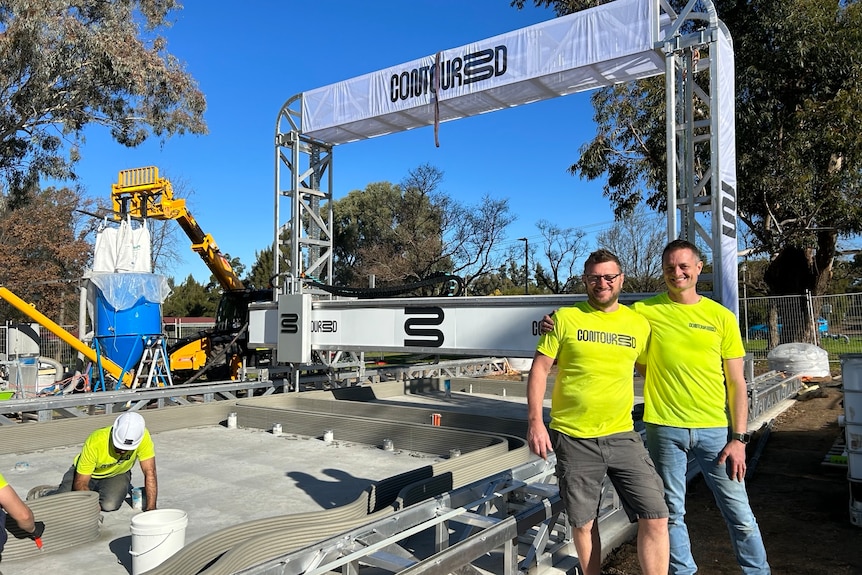 two men standing arm in arm on a construction site. 