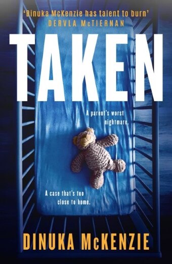 The book cover of Taken by Dinuka Mckenzie, featuring a blue tinted baby's cot with a toy bear