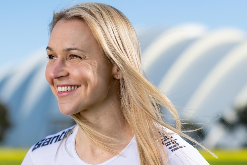 A blond woman smiling wearing a cycling suit