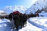 Afghan men carry the body of a victim of avalanches