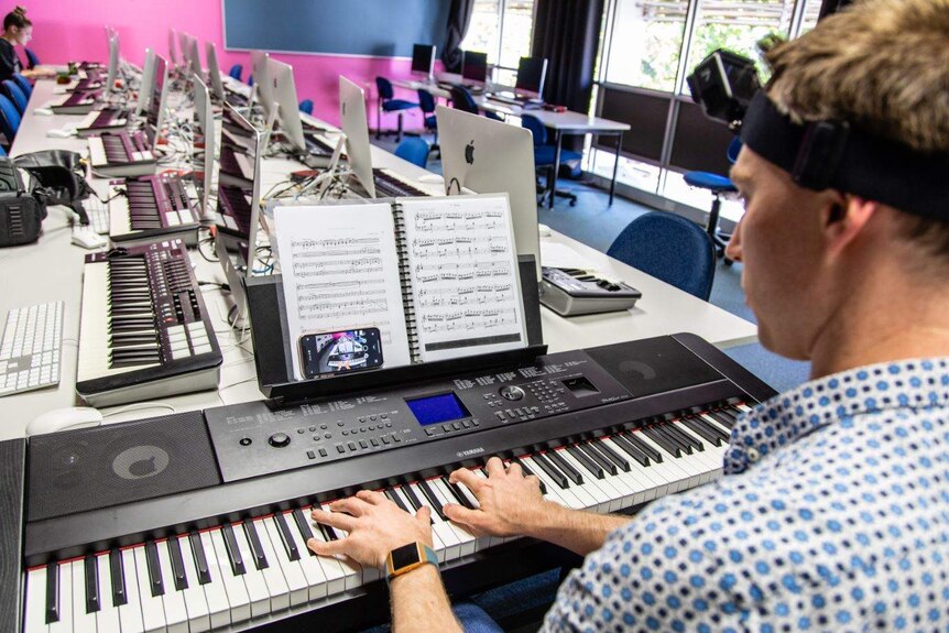 Craig plays a piece of music, while looking at a mobile that appears to be streaming what the GoPro on his head is filming.