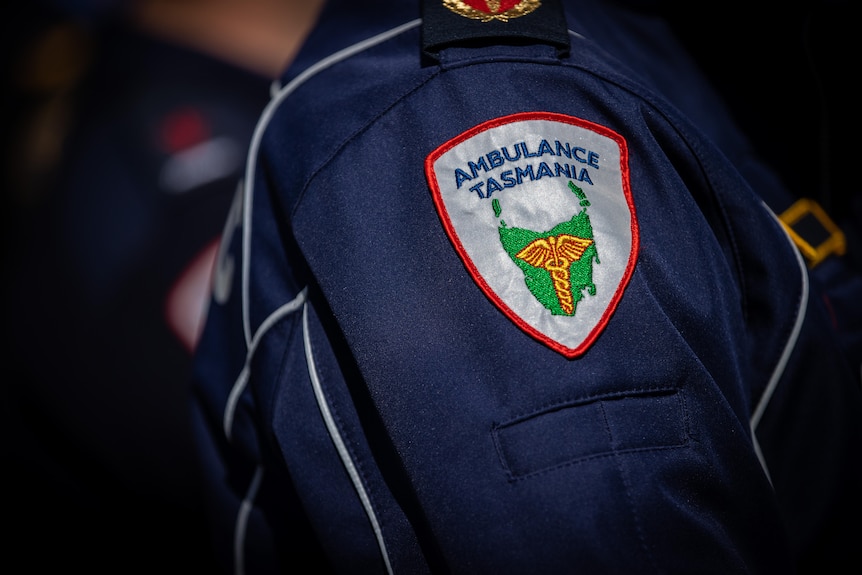 A badge on a man's arm reading Ambulance Tasmania