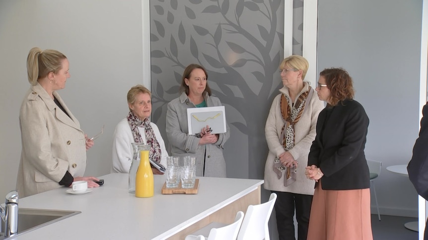 Women standing around a bench top looking at each other