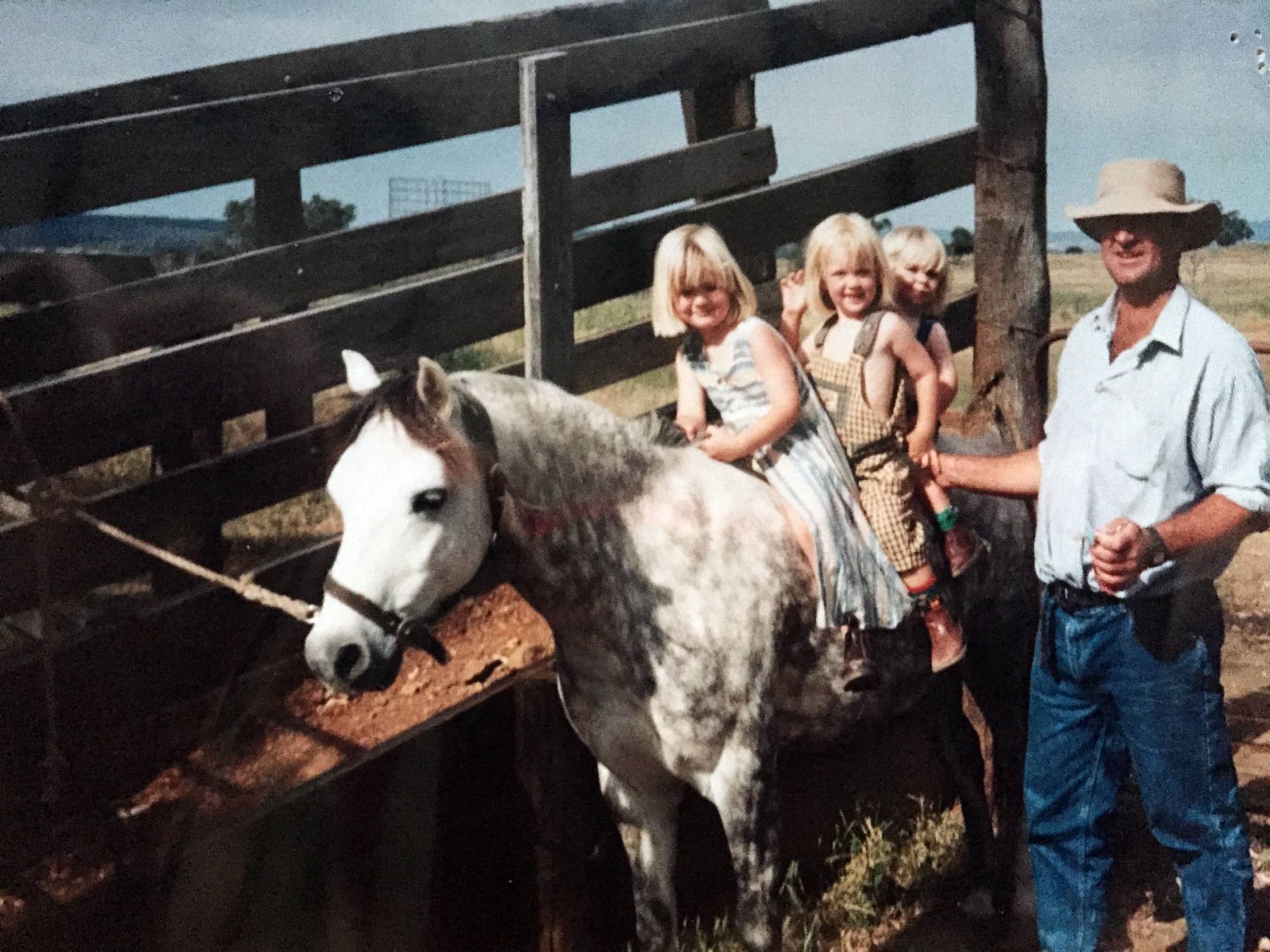 A photo of three little girls sitting on a dapple grey horse.