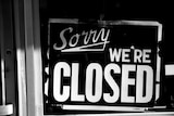A sign in a shop window saying "Sorry we're closed".
