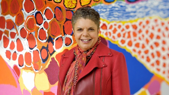 Professor Deborah Cheetham AO in front of an Indigenous art mural