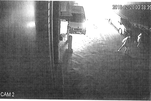 black and white still from CCTV vision showing two men running from a burning van