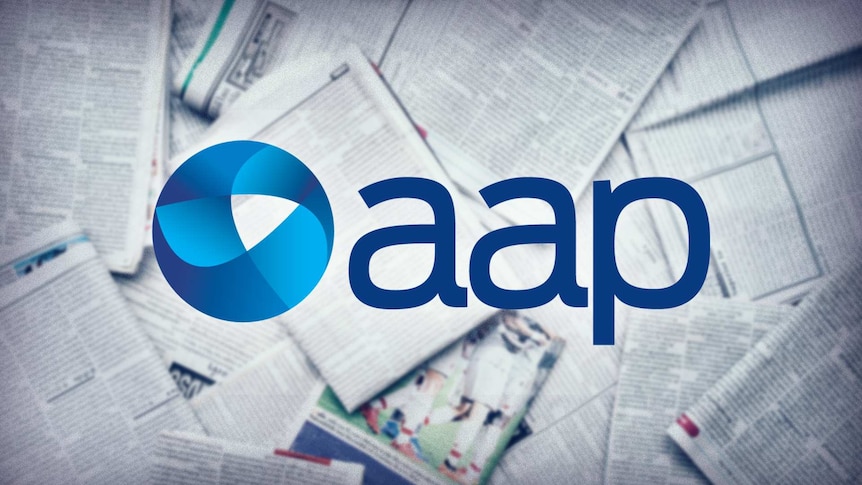 The AAP logo and newspapers blurred in the background.