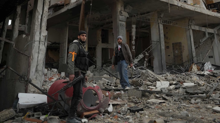 Free Syrian Army members near damaged buildings in Daraya