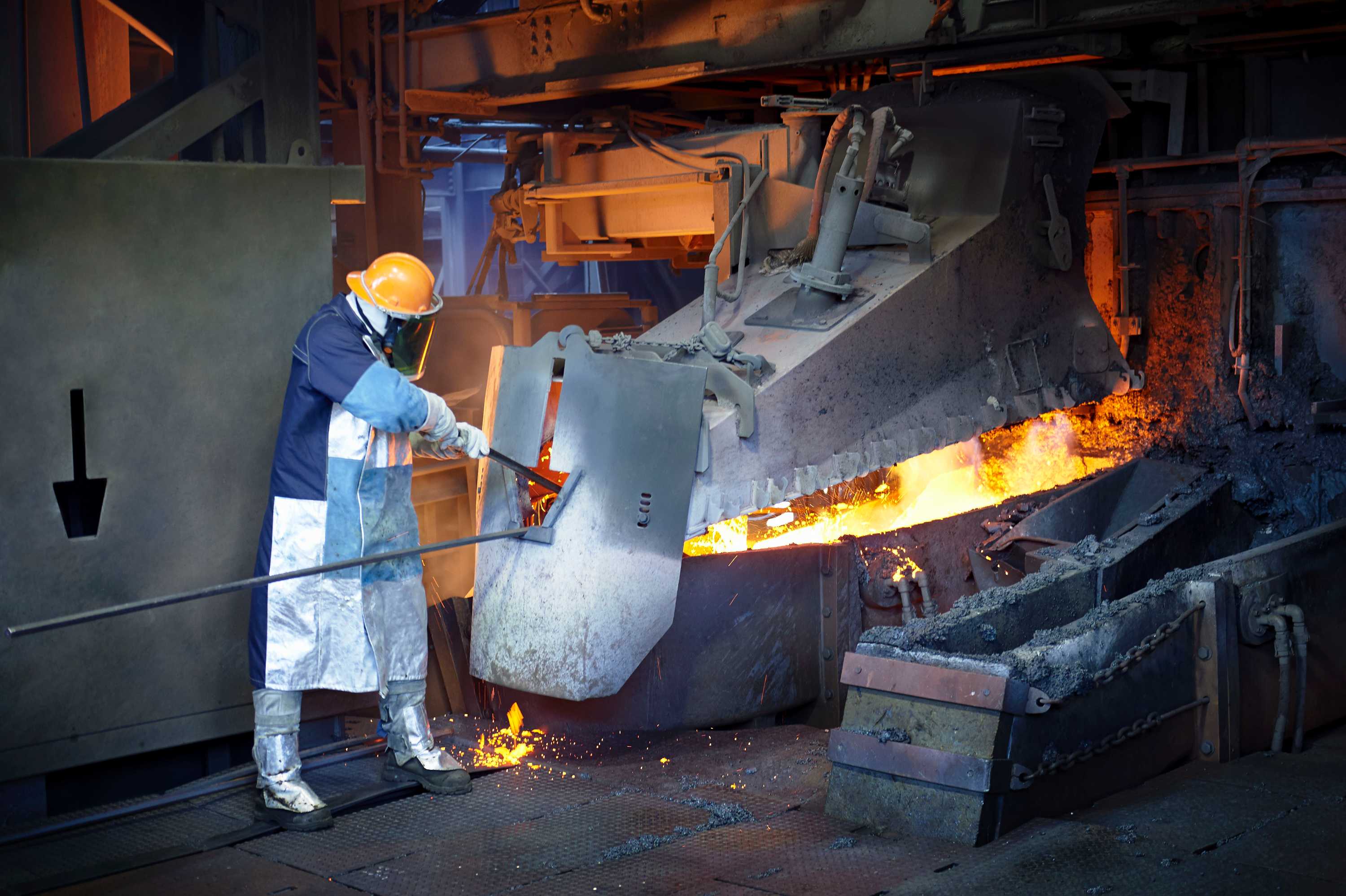 A man works in a furnace wearing protective equipment.
