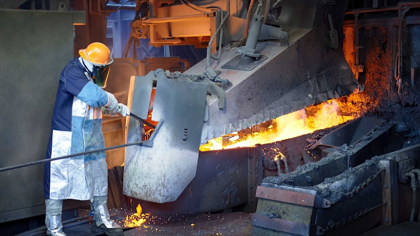 A man works in a furnace wearing protective equipment.