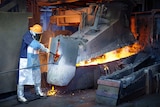 A man works in a furnace wearing protective equipment.