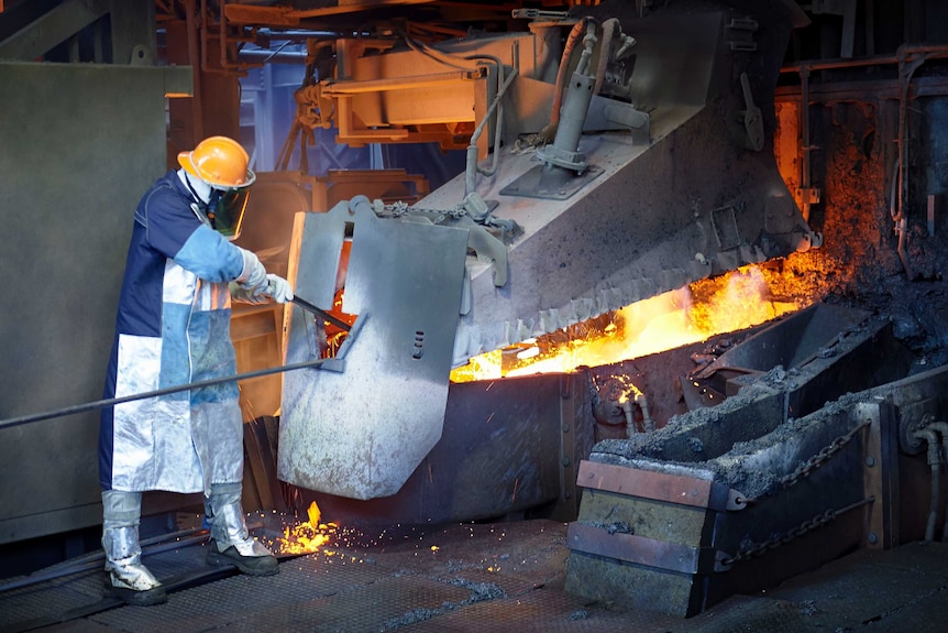 A man works in a furnace wearing protective equipment.