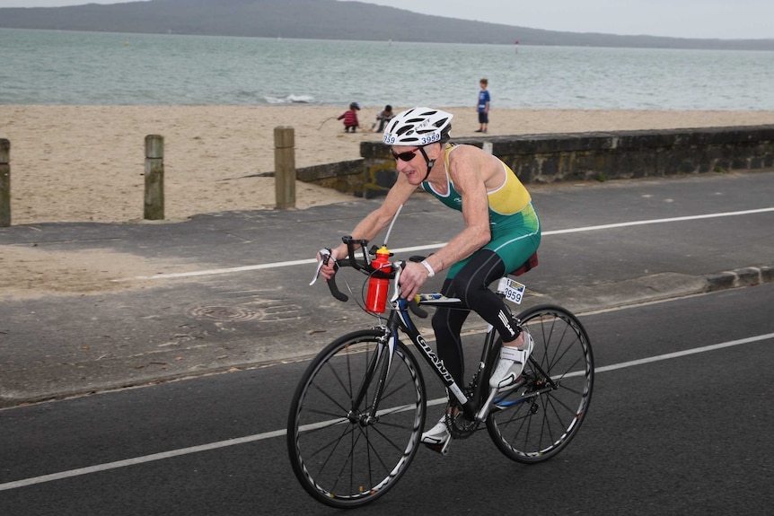 Keith Pearce cycling in a triathlon in an Australian uniform