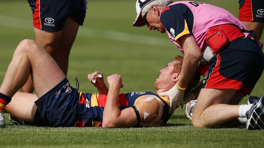 Adelaide's Tom Lynch is helped by medical staff after being injured against Geelong at Port Lincoln.