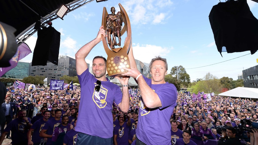 Cameron Smith and Craig Bellamy lift the premiership trophy in front of Storm fans