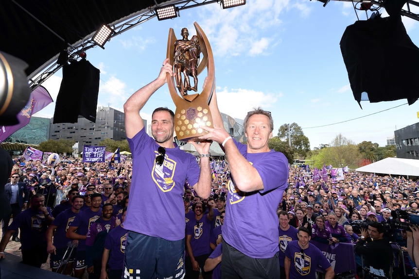 Cameron Smith and Craig Bellamy lift the premiership trophy in front of Storm fans