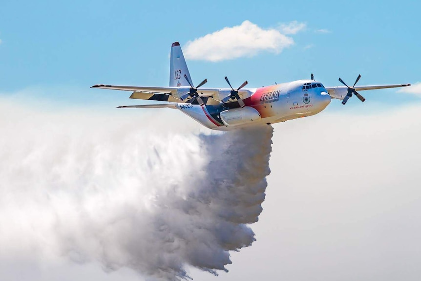 A huge aircraft trails fire-retardant as it soars through the air.
