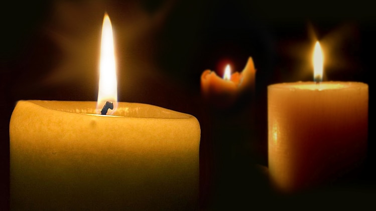 Three candles burning against a dark background.