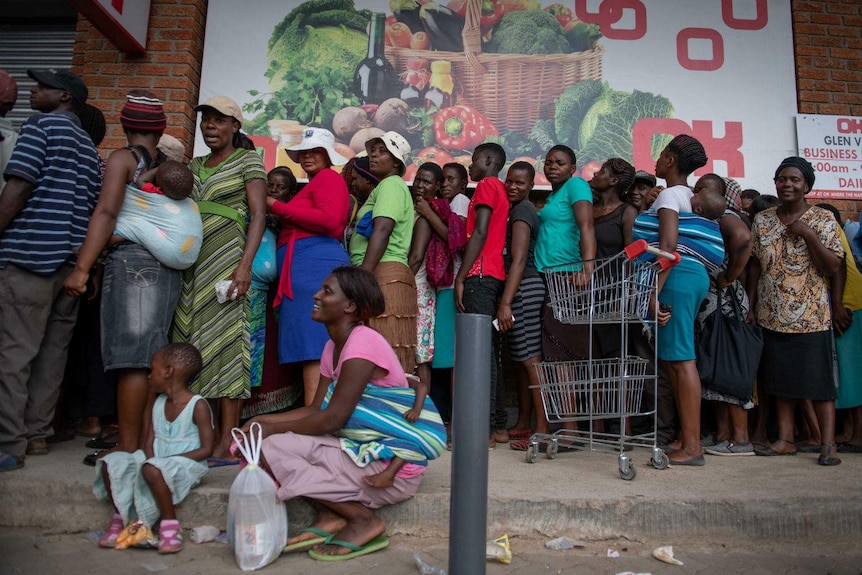 a queue of people stand outside a shop