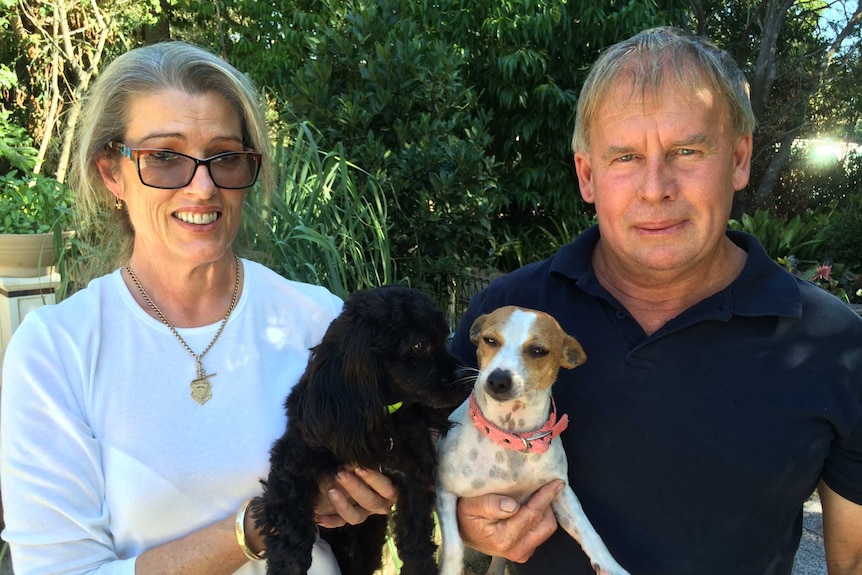 Angie and Peter hold two puppies in arms.