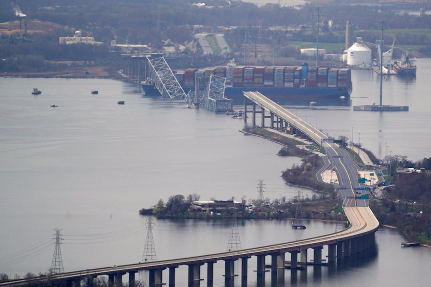 A view of a bridge from far away with its middle section collapsed into the water after a ship crash