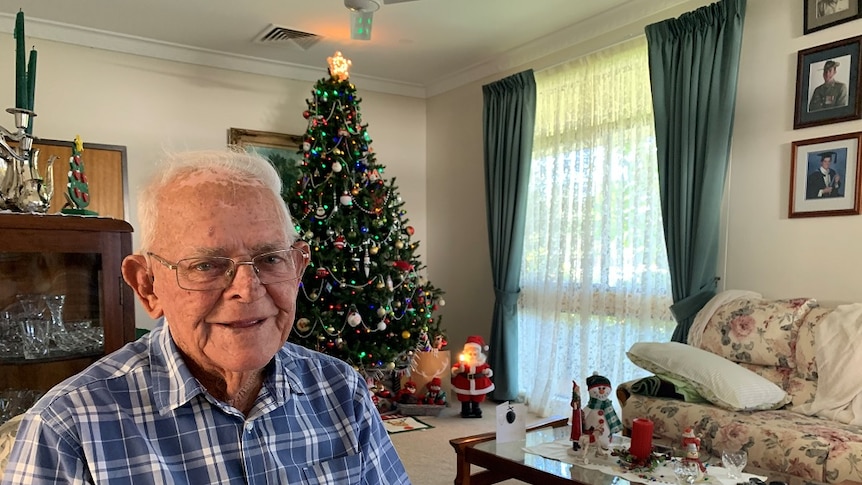 Sydney Kinsman stands in front of his Christmas tree