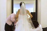 Dress designers check the fit of a wedding dress
