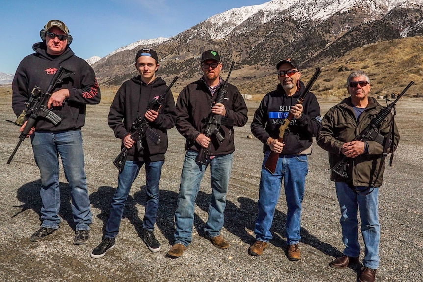 A line of men armed with guns in a wide valley in Utah