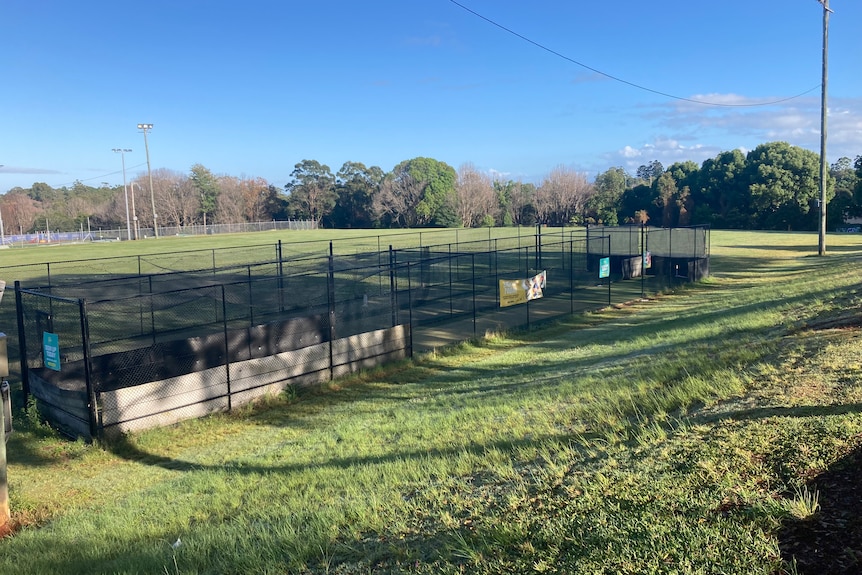 A photo of an empty field with cricket ets in the foreground.