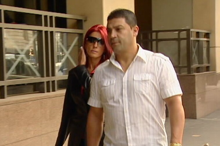 A man and a woman walking in the street outside a court.
