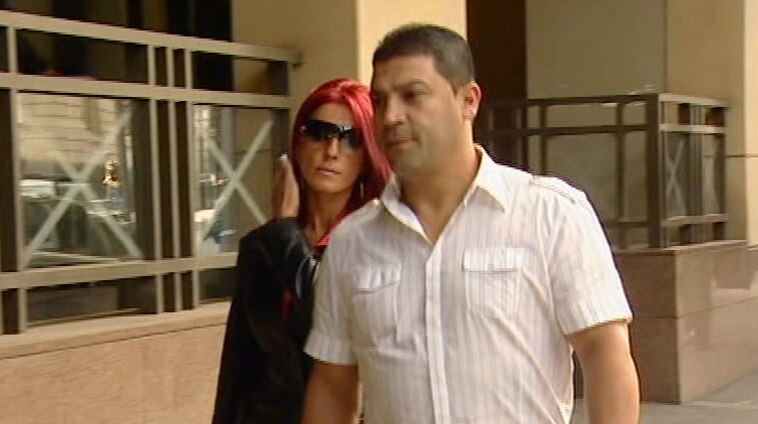 A man and a woman walking in the street outside a court.