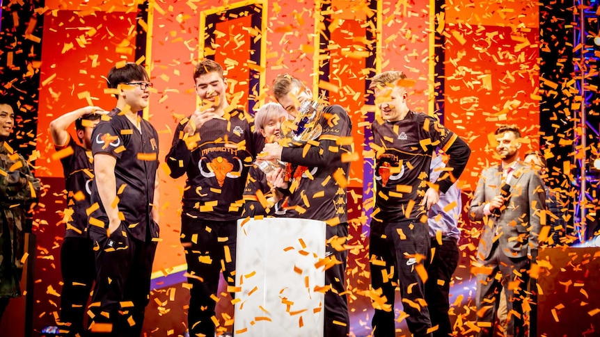 Confetti falls from the ceiling as the League of Legends team Mammoth hold their trophy at the Melbourne Esports Open.