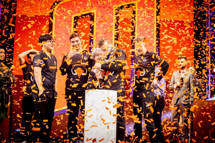 Confetti falls from the ceiling as the League of Legends team Mammoth hold their trophy at the Melbourne Esports Open.