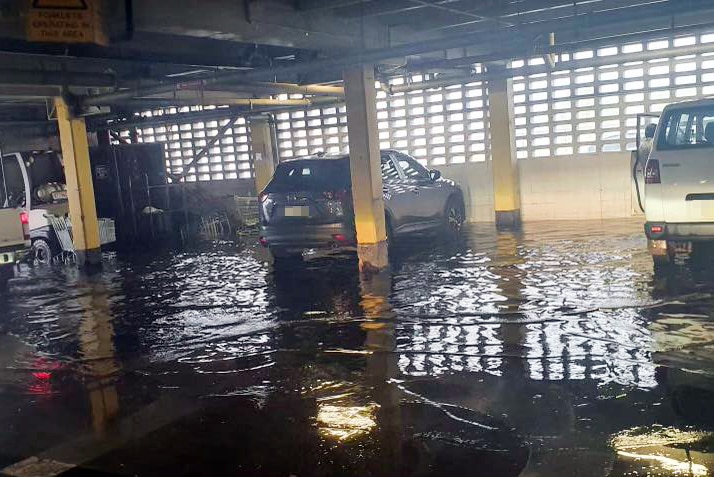 Cars in an underground carpark. Water laps at the tyres.