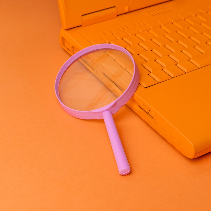Orange laptop with pink magnifying glass on keyboard