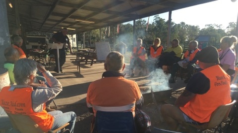 Volunteers gather around fire at their camp before heading off to work on properties.