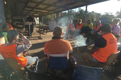 Volunteers gather around fire at their camp before heading off to work on properties.