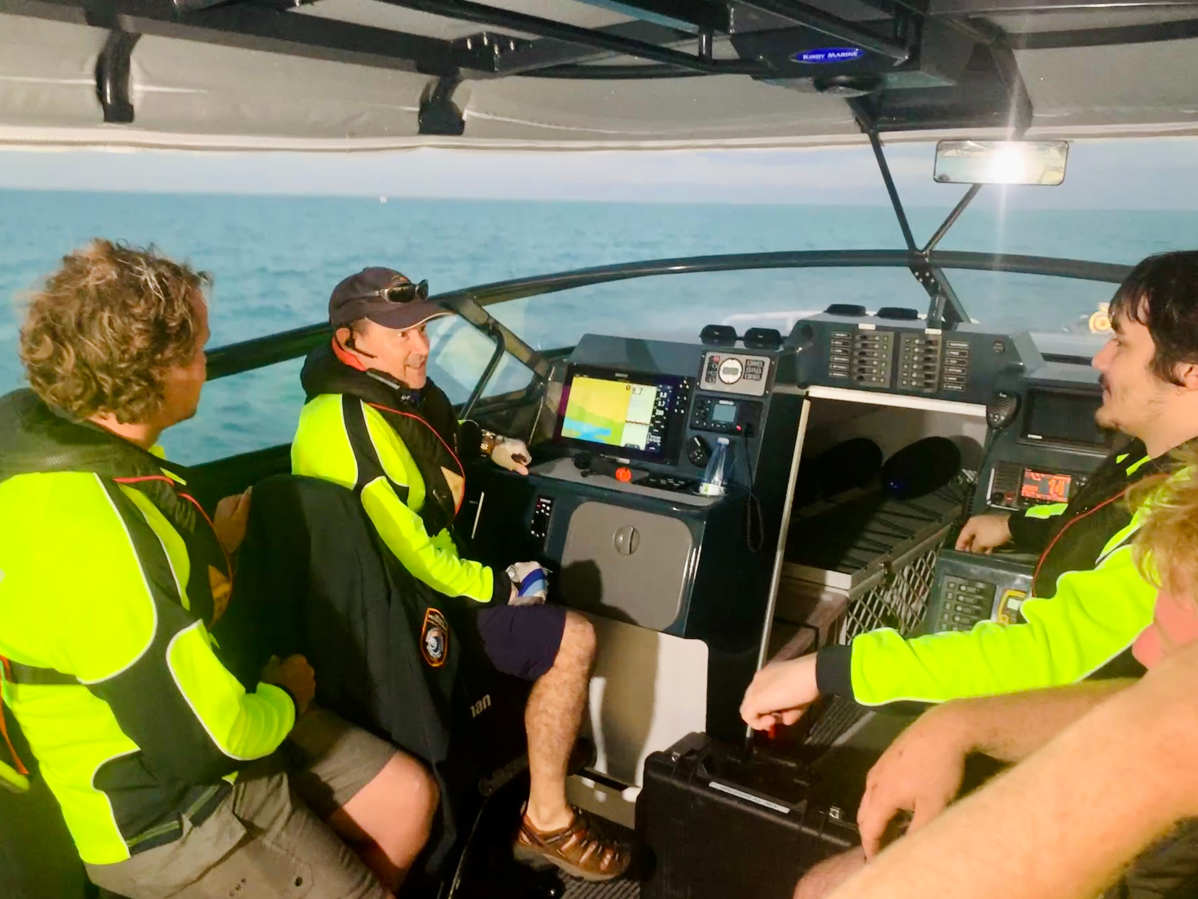 A group of men in fluro shirts sit in a boat.