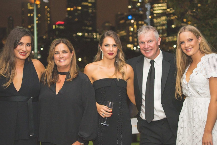 Danny Frawley, his wife and three daughters smile happily at an event.