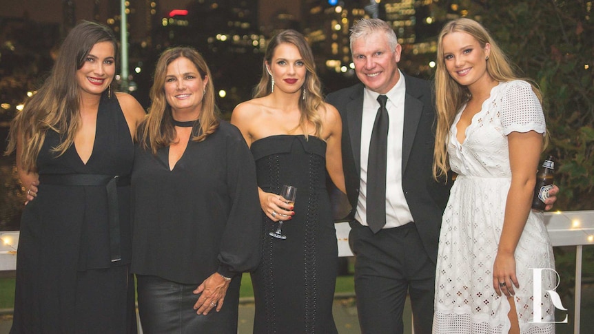 Danny Frawley, his wife and three daughters smile happily at an event.